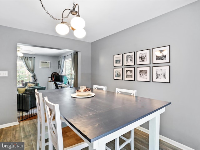 dining room featuring ceiling fan with notable chandelier, wood finished floors, baseboards, and a wall mounted air conditioner