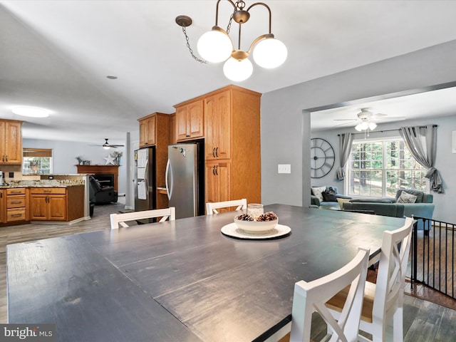 dining room with ceiling fan with notable chandelier and wood finished floors