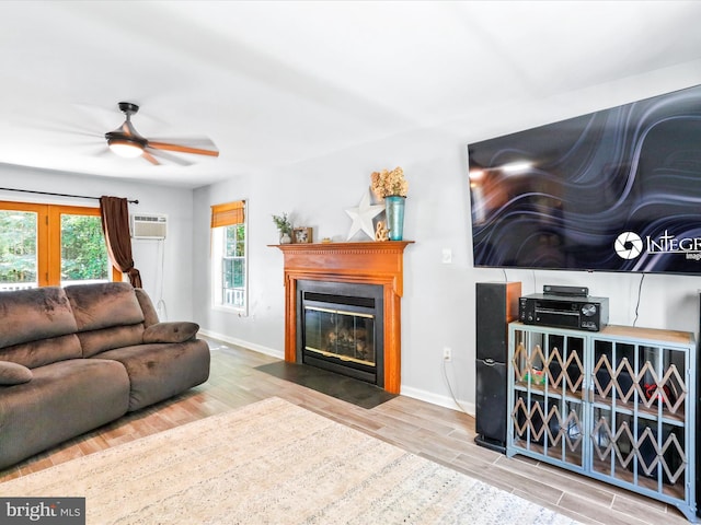 living room featuring a fireplace with flush hearth, wood finished floors, baseboards, and ceiling fan