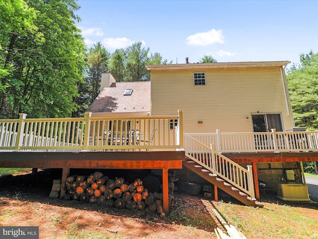 back of property with stairway, a wooden deck, and a chimney