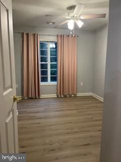 spare room with a ceiling fan, wood finished floors, and baseboards