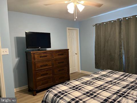 bedroom featuring baseboards, light wood-style floors, and a ceiling fan