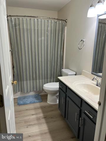 bathroom featuring toilet, vanity, a shower with curtain, and wood finished floors