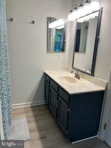 full bathroom featuring vanity, wood finished floors, and baseboards