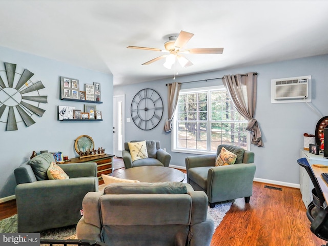 living room with visible vents, a wall mounted air conditioner, baseboards, and wood finished floors