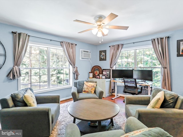 living area with an AC wall unit, plenty of natural light, wood finished floors, and ceiling fan