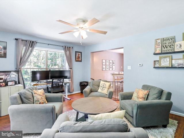 living room featuring baseboards, wood finished floors, and a ceiling fan