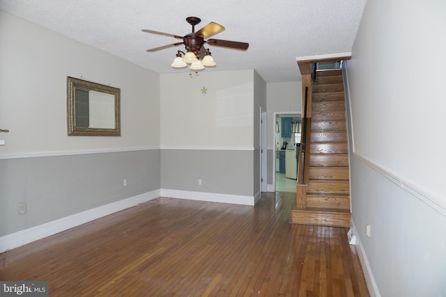 interior space featuring baseboards, stairs, a textured ceiling, a ceiling fan, and wood-type flooring