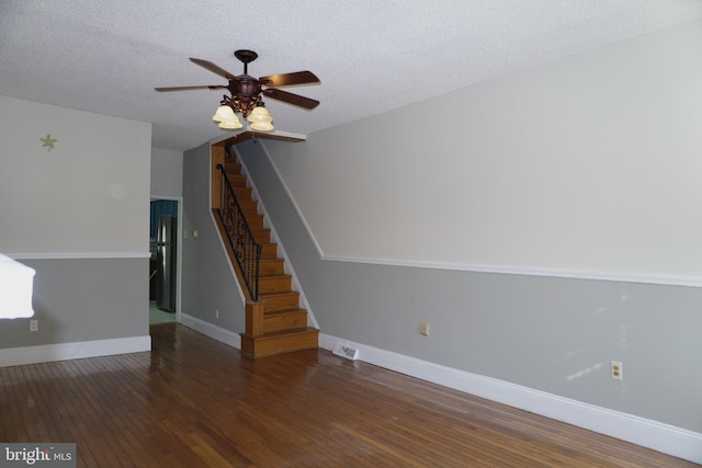 spare room with a textured ceiling, stairs, baseboards, and hardwood / wood-style floors