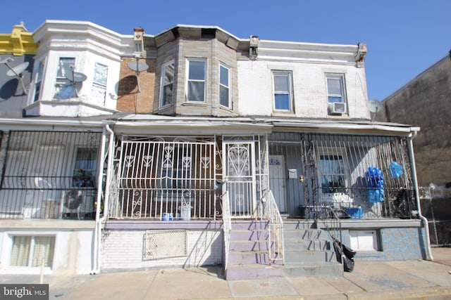 townhome / multi-family property featuring cooling unit, covered porch, and brick siding