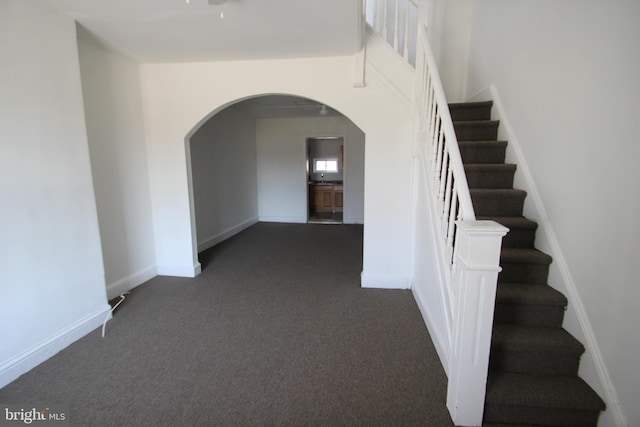 interior space featuring baseboards, arched walkways, and carpet floors