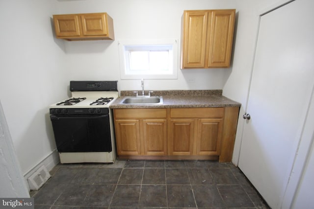 kitchen featuring dark countertops, visible vents, gas stove, and a sink