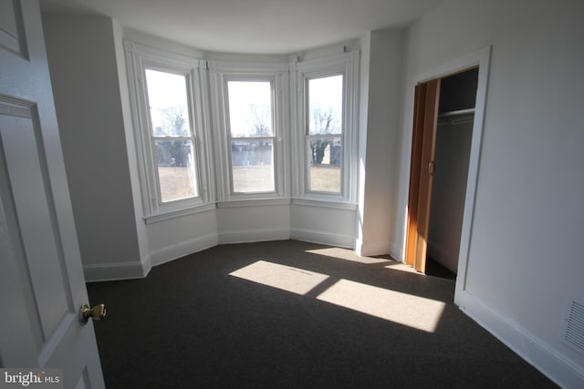 unfurnished bedroom featuring baseboards and dark carpet