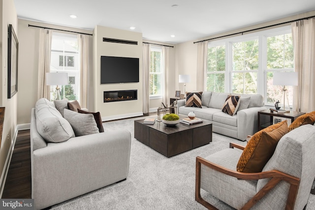 living room featuring plenty of natural light, recessed lighting, and a glass covered fireplace