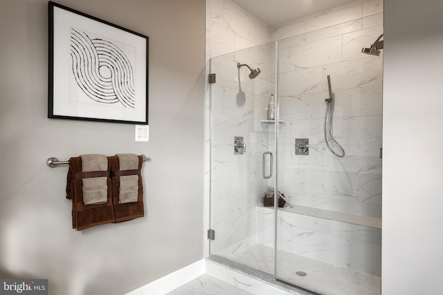 bathroom with baseboards, marble finish floor, and a marble finish shower