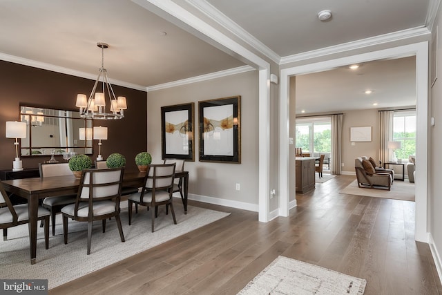 dining area featuring an inviting chandelier, wood finished floors, baseboards, and ornamental molding