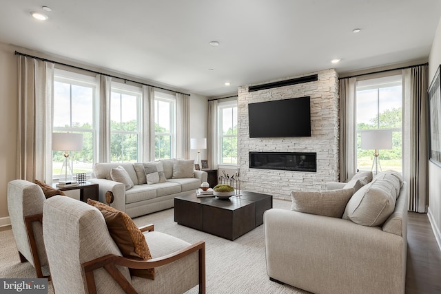 living room featuring a wealth of natural light, a stone fireplace, light wood-style flooring, and recessed lighting