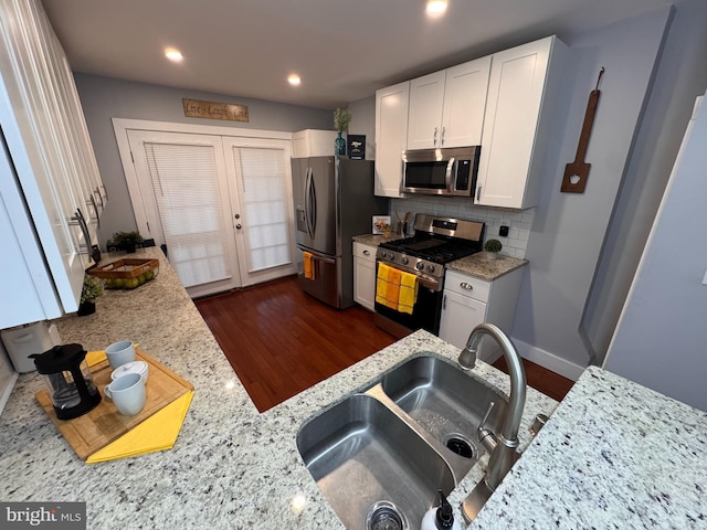 kitchen with a sink, decorative backsplash, stainless steel appliances, white cabinets, and french doors