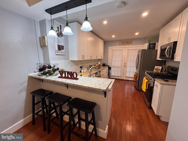 kitchen featuring white cabinets, light stone counters, dark wood-style flooring, and stainless steel appliances