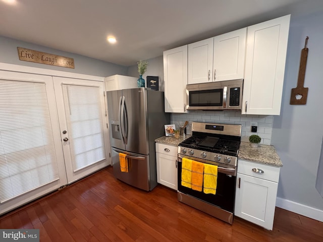 kitchen with dark wood-type flooring, light stone counters, tasteful backsplash, white cabinetry, and stainless steel appliances