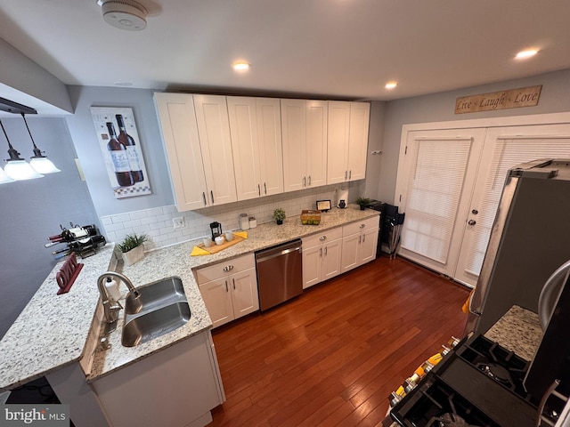 kitchen featuring dark wood finished floors, a sink, decorative backsplash, stainless steel appliances, and white cabinetry