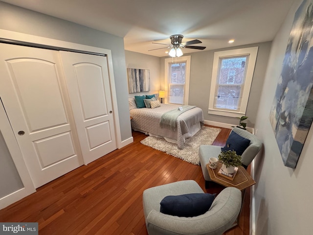 bedroom with baseboards, wood finished floors, a closet, and ceiling fan