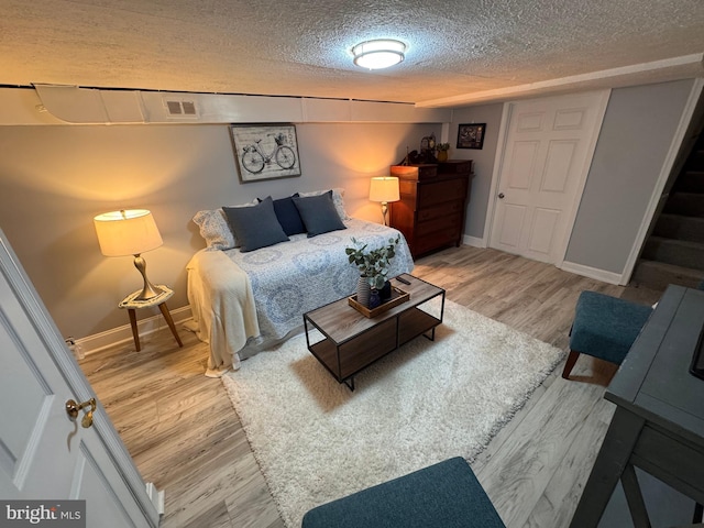 bedroom featuring visible vents, baseboards, a textured ceiling, and wood finished floors