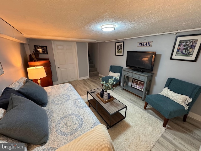 living area featuring stairway, baseboards, a textured ceiling, and wood finished floors