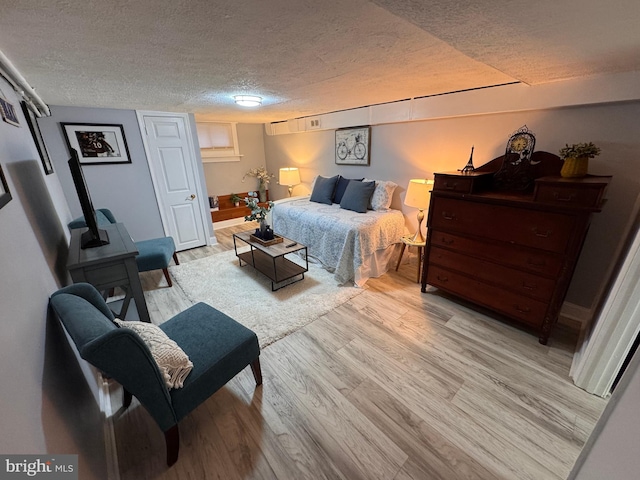 bedroom with a textured ceiling and light wood finished floors