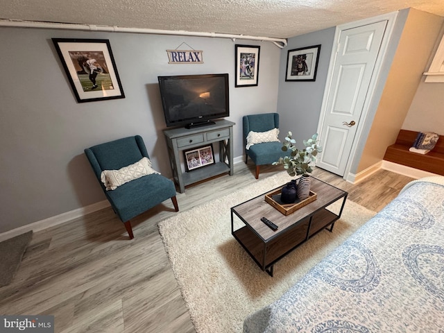 living area featuring baseboards, a textured ceiling, and wood finished floors