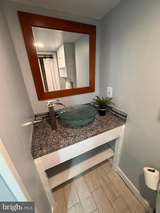 bathroom featuring vanity, wood finished floors, and baseboards