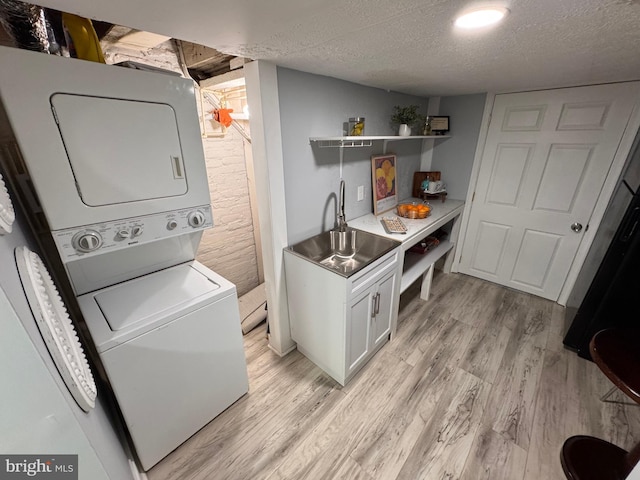 laundry room with light wood finished floors, stacked washer and clothes dryer, and a textured ceiling