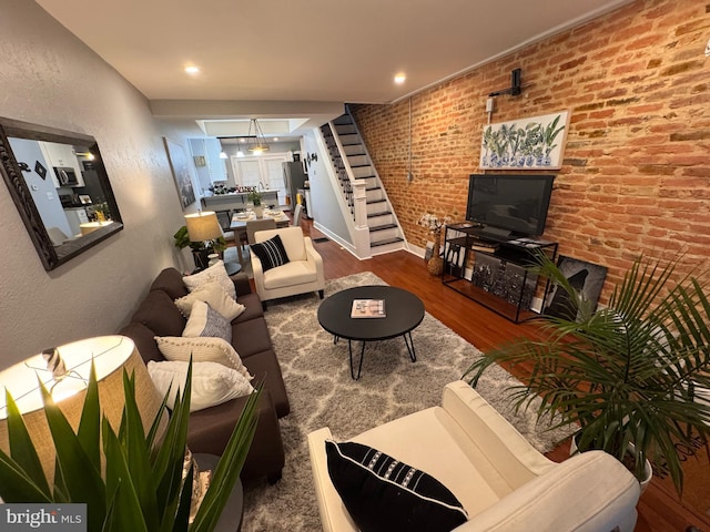 living area featuring brick wall, wood finished floors, stairs, recessed lighting, and a textured wall