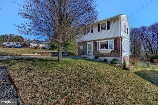 colonial-style house featuring brick siding, a front yard, and fence