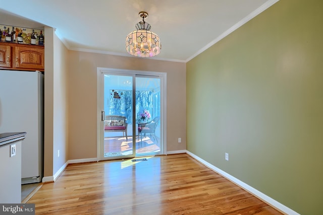 unfurnished dining area with baseboards, light wood-type flooring, and ornamental molding