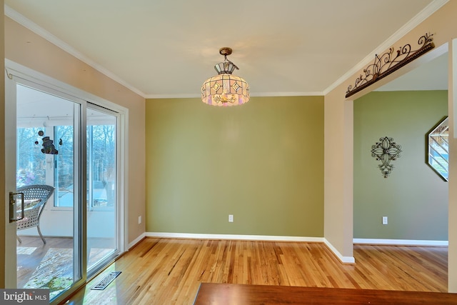 unfurnished dining area featuring visible vents, light wood-style flooring, baseboards, and ornamental molding