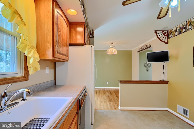 kitchen with visible vents, brown cabinets, a sink, crown molding, and light countertops