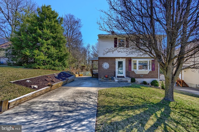 view of front of house with brick siding, entry steps, concrete driveway, and a front yard