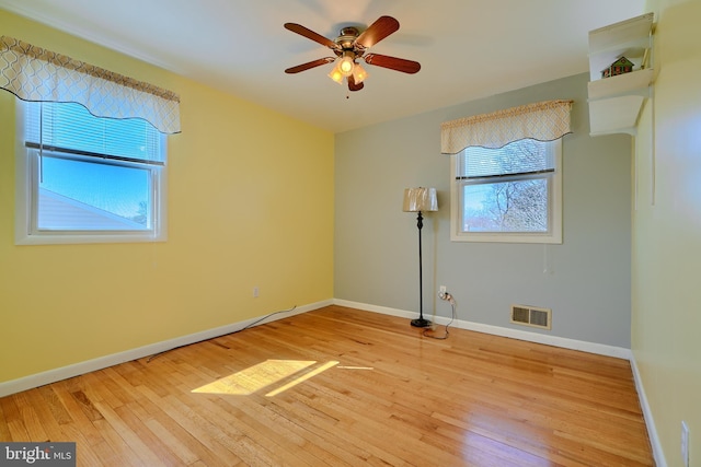 unfurnished room featuring baseboards, visible vents, light wood finished floors, and ceiling fan