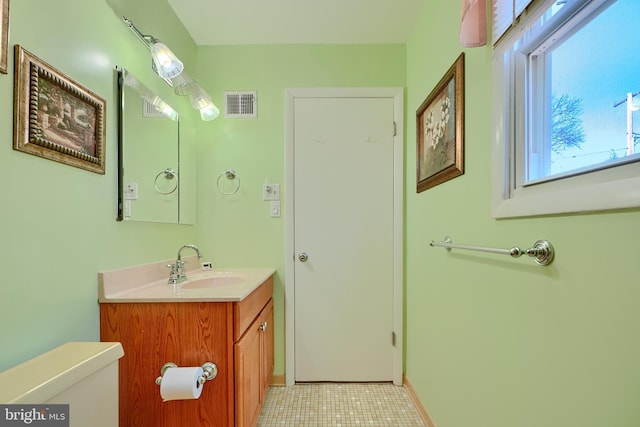 bathroom featuring visible vents, toilet, vanity, and baseboards