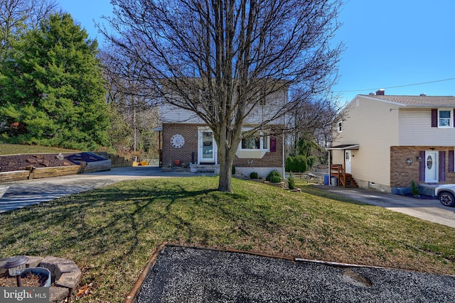 view of front of house featuring entry steps, concrete driveway, and a front yard