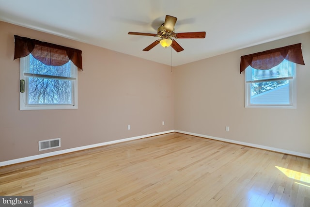 spare room with hardwood / wood-style flooring, baseboards, visible vents, and ceiling fan