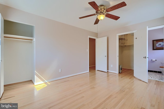 unfurnished bedroom with a spacious closet, baseboards, light wood-style floors, a closet, and a ceiling fan