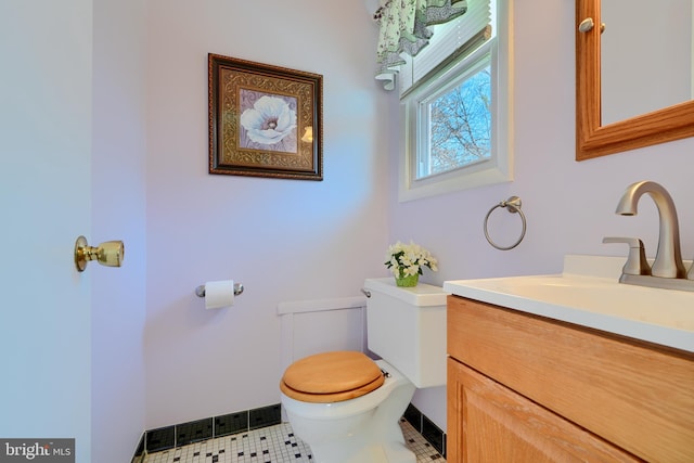 half bathroom with tile patterned flooring, toilet, and vanity