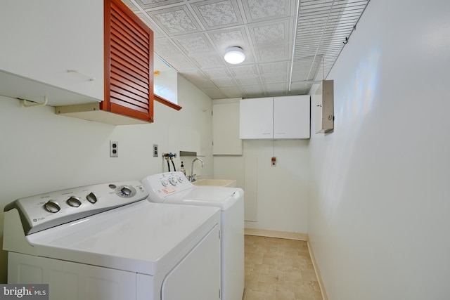 clothes washing area featuring washer and clothes dryer, cabinet space, baseboards, and a sink