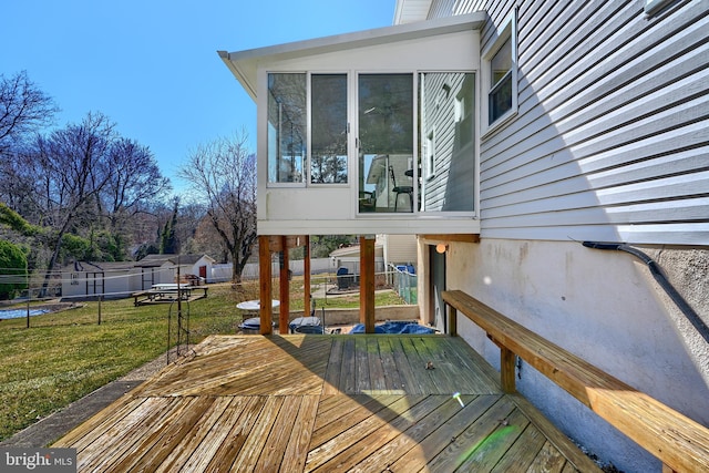 deck with an outbuilding, fence, a shed, a yard, and a sunroom