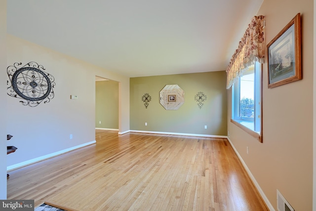 empty room featuring visible vents, baseboards, and light wood finished floors