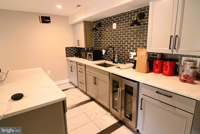 kitchen featuring marble finish floor, beverage cooler, a sink, recessed lighting, and decorative backsplash