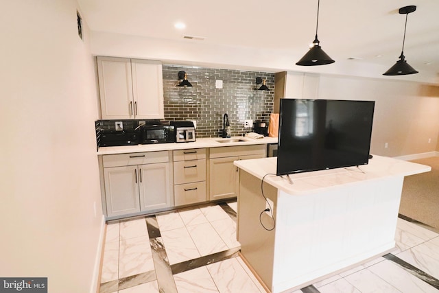 kitchen with decorative backsplash, light countertops, marble finish floor, and a sink