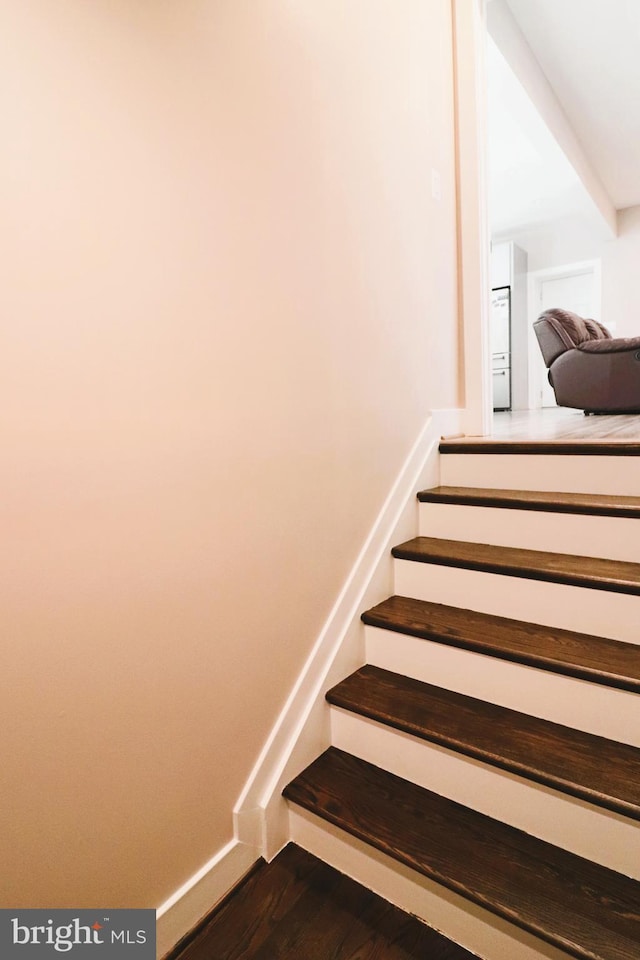 staircase with baseboards and wood finished floors